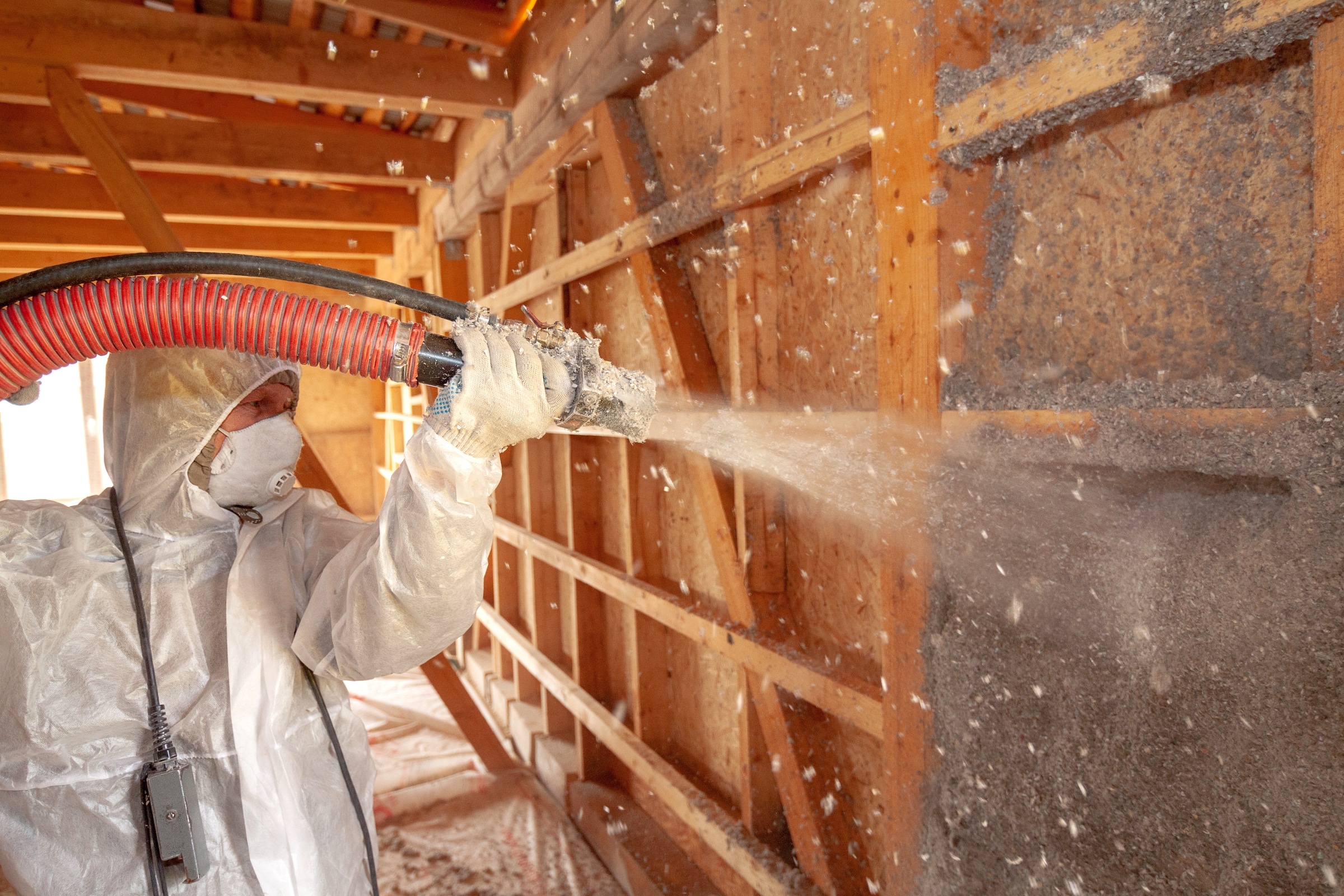 Worker applying blown cellulose insulation